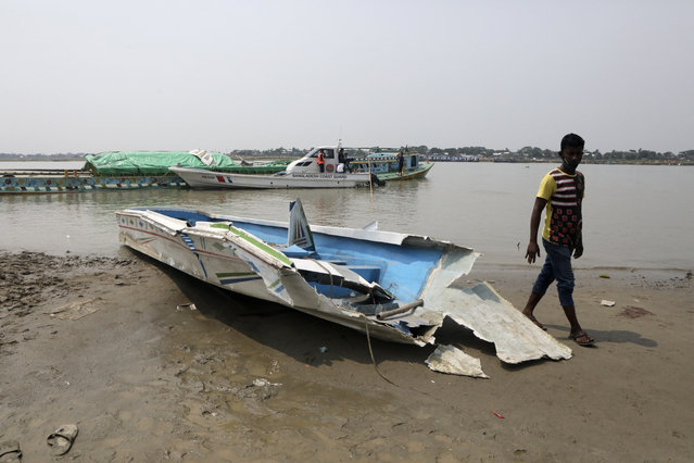 A man walks past the mangled remains of a speedboat that overturned Monday morning after hitting a cargo boat in River Padma at the Kanthalbari ferry terminal in Madaripur, central Bangladesh, Monday, May 3, 2021. More than two dozen people were killed. (Photo by Abdul Goni/AP Photo)