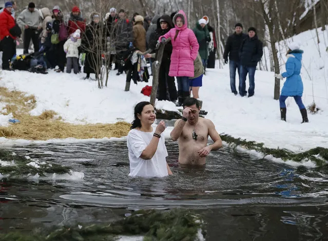 People cross themselves as they take a dip in a lake during Orthodox Epiphany celebrations in Kiev, Ukraine, January 19, 2016. (Photo by Gleb Garanich/Reuters)