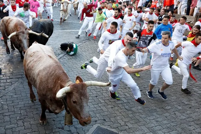 Revellers run during the running of the bulls at the San Fermin festival in Pamplona, Spain on July 7, 2022. (Photo by Vincent West /Reuters)