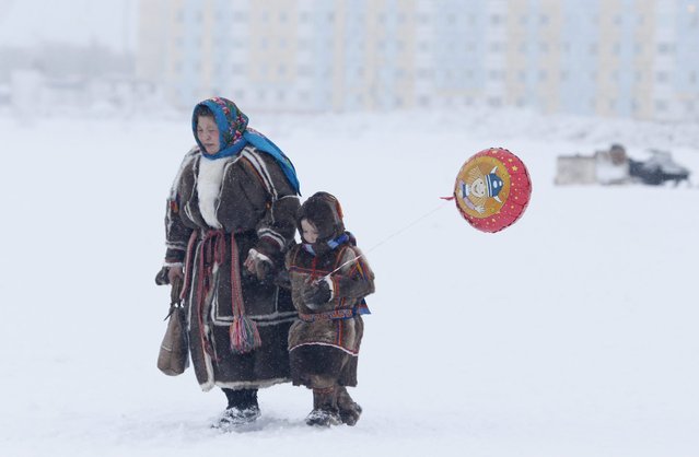 In this photo taken on Sunday, March 15, 2015, a Nenets woman and her child attend the Reindeer Herder's Day holiday in the city of Nadym, in Yamal-Nenets Region, 2500 kilometers (about 1553 miles) northeast of Moscow, Russia. (Photo by Dmitry Lovetsky/AP Photo)
