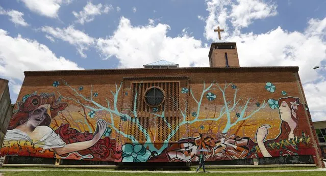 In this March 12, 2015 photo, a mural blankets a church wall in Bogota, Colombia. Street art has subsequently exploded across the city of 8 million. By one count, there are now more than 5,000 large paintings on walls or the sides of buildings, many now well-known to the tourists who sign up for guided graffiti tours on bicycle. (Photo by Fernando Vergara/AP Photo)