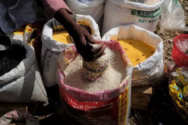 A rice vender fills a container at the Maché Tèt Dlo market in Port-au-Prince, Haiti, Tuesday, July 13, 2021. (Photo by Matias Delacroix/AP Photo)