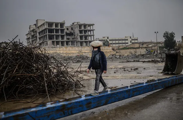 A young man carries a bag of bread on his head as he walks along a metalic beam in the northern Syrian city of Raqa on February 14, 2019. In 2014, jihadists of the Islamic State (IS) seized the city of Raqa from Syrian rebels. In October 2017, the Syrian Defence Forces (SDF) announces the full recapture of Raqa city, the capital of the eponymous province. (Photo by Bülent Kılıç/AFP Photo)