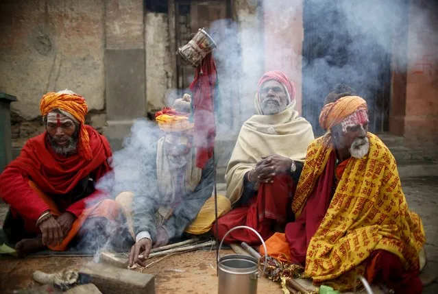 Hindu holy men, or sadhus, sit beside the fire at the premises of Pashupatinath Temple in Kathmandu, Nepal March 6, 2016. (Photo by Navesh Chitrakar/Reuters)
