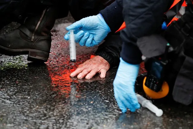 A police officer applies a solution on the glued hand of an Insulate Britain activist blocking a motorway junction near Heathrow Airport in London, Britain, October 1, 2021. (Photo by Peter Cziborra/Reuters)
