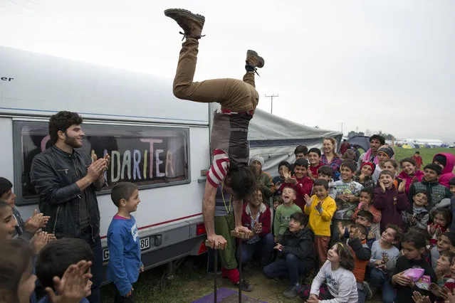 Children are enterained by a performer at the Idomeni refugee camp on the Greek-Macedonia border on March 6, 2016 in Idomeni, Greece. Doctors are warning that conditions at the camp are becoming dangerous for children, with medics dealing with a range of illnesses, including hypothermia. The transit camp at the border is becoming increasingly overcrowded as thousands of refugees continue to arrive from Athens and the Greek Islands. (Photo by Dan Kitwood/Getty Images)