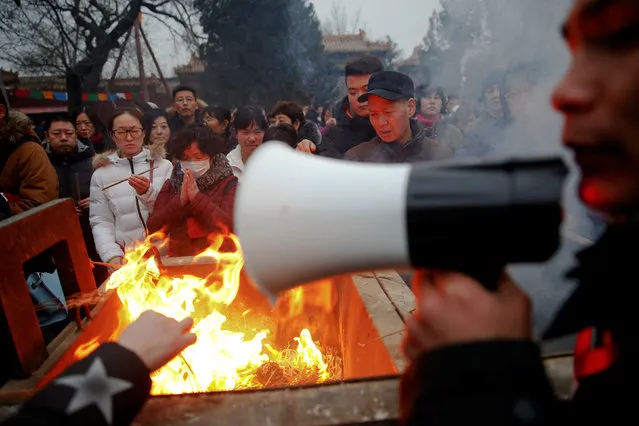 A man uses a megaphone to give instructions as people burn incense sticks and pray for good fortune at Yonghegong Lama Temple on the first day of the Lunar New Year of the Rooster in Beijing, China January 28, 2017. (Photo by Damir Sagolj/Reuters)