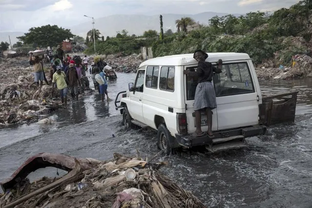 A girl laughs while traveling on a pickup to avoid getting wet due to a flooded street in Cite du Soleil district in Port-au-Prince, Haiti, Saturday October 2, 2021. (Photo by Rodrigo Abd/AP Photo)