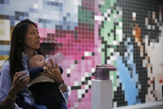 A woman feeds her baby in front of an art installation created by German artist Tobias Rehberger during the VIP preview of the art fair “Art Basel” in Hong Kong, Tuesday, March 22, 2016. (Photo by Kin Cheung/AP Photo)