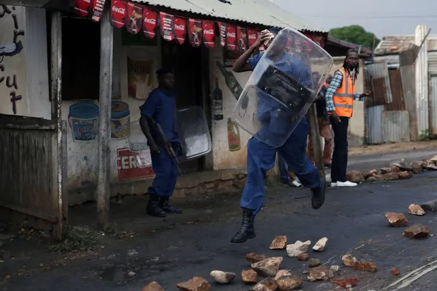 A police officer hit by a stone thrown by demonstrators runs as police uses bulldozers and water canons to clear the barricades in the Nyakabyga district of Bujumbura, Burundi, Friday, May 8, 2015. President Pierre Nkurunziza's officially filed to become a candidate for a potential third term in office. (Photo by Jerome Delay/AP Photo)