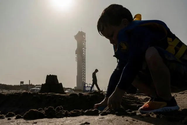 A boy builds a sandcastle on the beach as SpaceX's next-generation Starship spacecraft atop its powerful Super Heavy rocket is prepared for a third launch from the company's Boca Chica launchpad on an uncrewed test flight, near Brownsville, Texas on March 13, 2024. (Photo by Cheney Orr/Reuters)