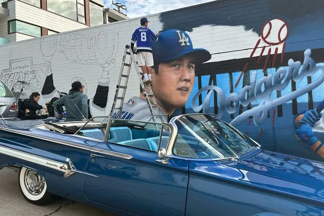 Artist Gustavo Zermeno Jr., top center, paints a mural with the likeness of Los Angeles Dodgers baseball player Shohei Ohtani in the Hermosa Beach section of Los Angeles, Monday, December 18, 2023. Ohtani, a prized free agent, signed a multiyear, multimillion dollar contract with the Dodgers last week. (Photo by Eugene Garcia/AP Photo)