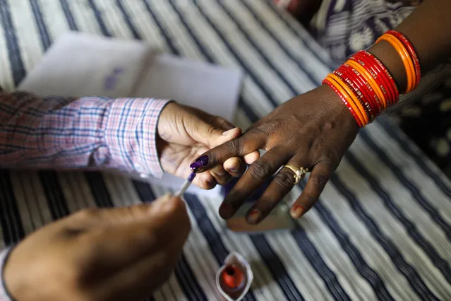 A polling officer puts indelible ink mark on the index finger of an women voter at a polling station, on the outskirts of Varanasi, India, Sunday, May 19, 2019. Indians are voting in the seventh and final phase of national elections, wrapping up a 6-week-long long, grueling campaign season with Prime Minister Narendra Modi’s Hindu nationalist party seeking reelection for another five years. Counting of votes is scheduled for May 23. (Photo by Rajesh Kumar Singh/AP Photo)