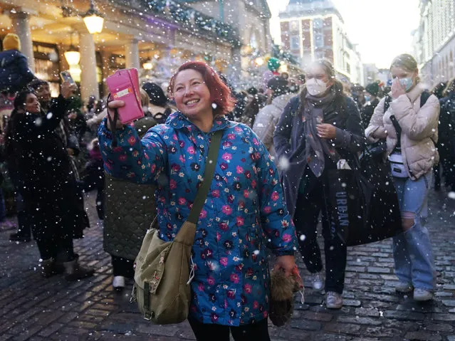 Artificial snow is sprayed in the air as people visit Covent Garden in London, United Kingdom on the first Saturday of December 2021. (Photo by Yui Mok/PA Images via Getty Images)