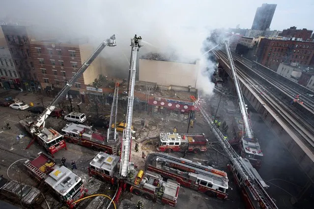 Firefighters battle a fire after a building collapses in the East Harlem neighborhood of New York, Wednesday, March 12, 2014. (Photo by John Minchillo/AP Photo)