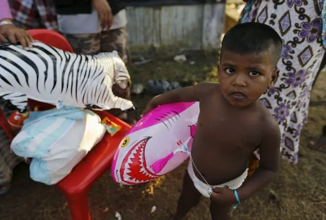 A Rohingya migrant child, who arrived in Indonesia by boat, holds a shark balloon inside a temporary compound for refugees in Kuala Cangkoi village in Lhoksukon, Indonesia's Aceh Province May 17, 2015. (Photo by Reuters/Beawiharta)