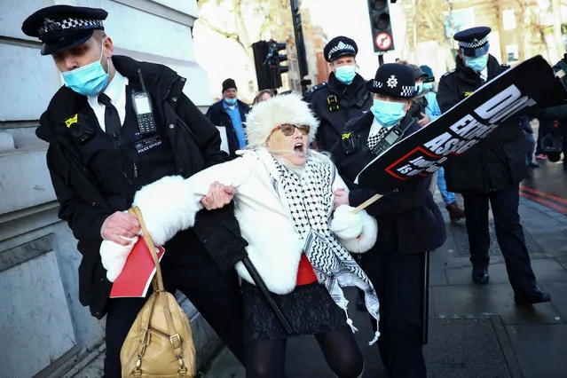 Police officers detain a woman holding a placard outside the Westminster Magistrates Court as Julian Assange's lawyers seek bail for their client in London, Britain on January 6, 2021. (Photo by Hannah McKay/Reuters)