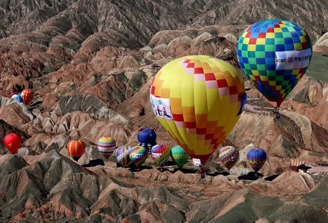Hot air balloons fly over Qicai Danxia scenic area during a hot air balloon festival in Zhangye, Gansu province, China on July 19, 2019. (Photo by Reuters/China Stringer Network)