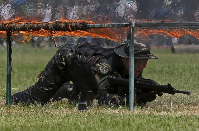 A People's Liberation Army (PLA) soldier crawls underneath fire during an anti-terrorist drill, at a PLA naval base in Hong Kong, China July 1, 2015. (Photo by Bobby Yip/Reuters)