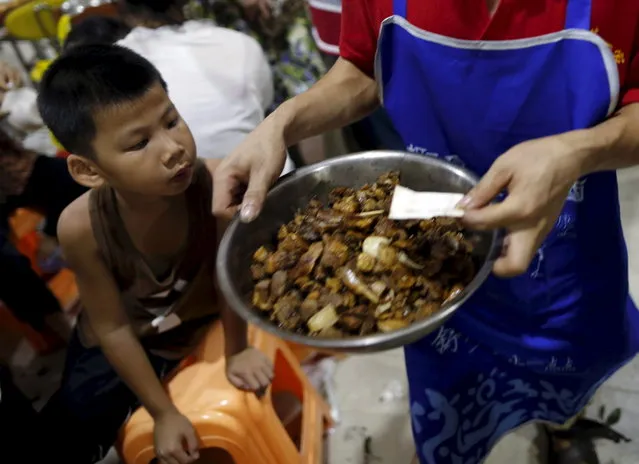 A boy looks at a bowl of dog meat carried by a waiter at a dog meat restaurant in Yulin, Guangxi Autonomous Region, June 21, 2015. (Photo by Kim Kyung-Hoon/Reuters)