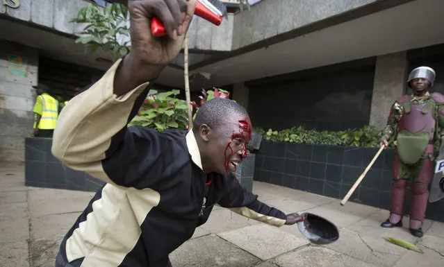An opposition supporter with a head wound crawls on his knees past riot police, begging them not to beat him, during a protest in downtown Nairobi, Kenya, Monday, May 16, 2016.. (Photo by Ben Curtis/AP Photo)