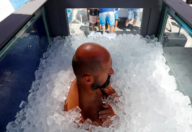 Austrian sportsman Josef Koeberl stands still in an ice-filled glass cabin as he tries to set a World Record of staying in ice in Vienna, Austria, August 10, 2019. (Photo by Leonhard Foeger/Reuters)