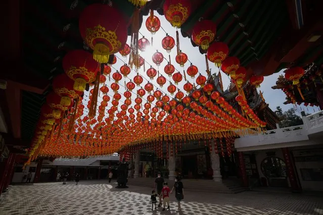 Tourists wearing face masks to help curb the spread of the coronavirus walk under traditional Chinese lanterns on display ahead of the Lunar New Year celebrations at a temple in Kuala Lumpur, Malaysia, Monday, January 10, 2022. Chinese around the world will be celebrating the start of the Year of Tiger on Feb. 1 in the Chinese lunar calendar. (Photo by Vincent Thian/AP Photo)