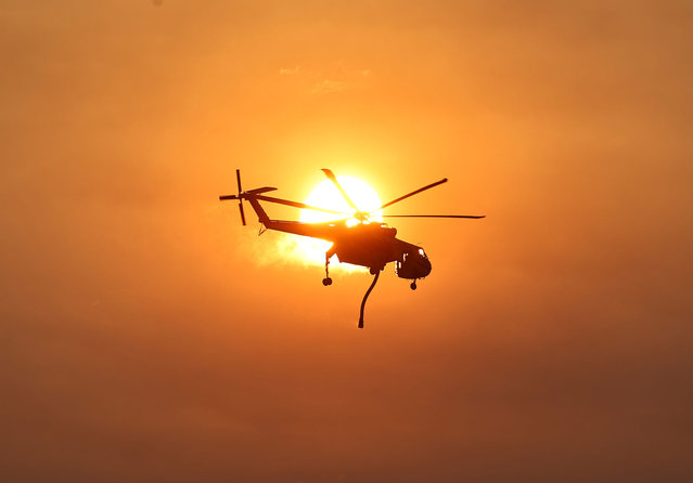 A firefighting helicopter flies as the Lake Fire burns in Los Padres National Forest with evacuation warnings in the area on July 6, 2024 near Los Olivos, California. The wildfire in Santa Barbara County has scorched over 13,000 acres amid a long-duration heat wave which is impacting much of California. (Photo by Mario Tama/Getty Images)