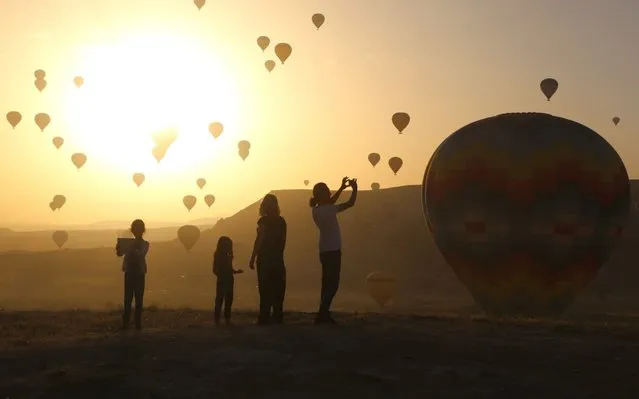 Hot air balloons glide over Goreme district on the first day of Eid al-Fitr during early morning at the historical Cappadocia region, located in Central Anatolia's Nevsehir province, Turkey on June 4, 2019. Cappadocia is known as a region which attracts tourists with hot air balloon rides over its cone-shaped rock formations. (Photo by Alpaslan Korukcu/Anadolu Agency/Getty Images)