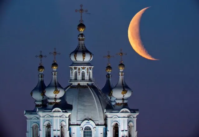 The moon rises in the sky above the domes of the Smolny Cathedral in St.Petersburg, Russia, Friday, April 25, 2014. One of St. Petersburg landmarks, the Smolny convent's main church was built between 1748 and 1764 by Italian architect Francesco Bartolomeo Rastrelli. (Photo by Dmitry Lovetsky/AP Photo)