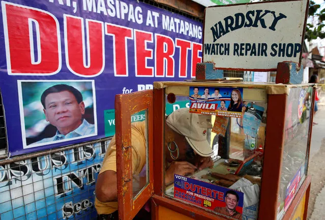 A watch maker and a supporter of President Rodrigo Duterte works at his sidewalk shop in front of a Duterte election campaign poster in Davao city in southern Philippines, May 10, 2016. (Photo by Erik De Castro/Reuters)