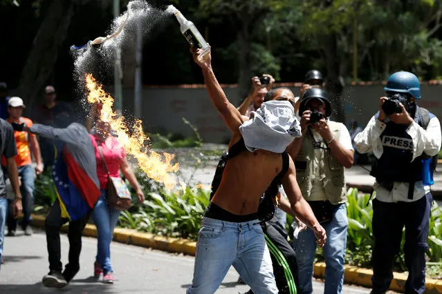 A demonstrator throws a molotov cocktail against riot policemen during a protest called by university students against Venezuela's government in Caracas, Venezuela, June 9, 2016. (Photo by Carlos Garcia Rawlins/Reuters)