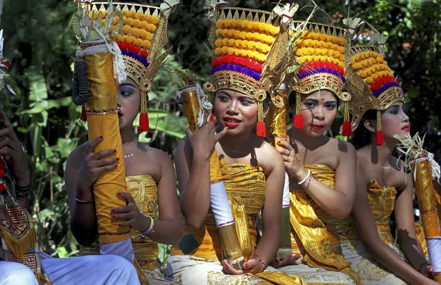 Balinese girls in traditional dress wait for a parade during the Bali Arts Festival in Bali, Indonesia, Saturday, June 10, 2017. A month-long annual festival started on Saturday. (Photo by Firdia Lisnawati/AP Photo)