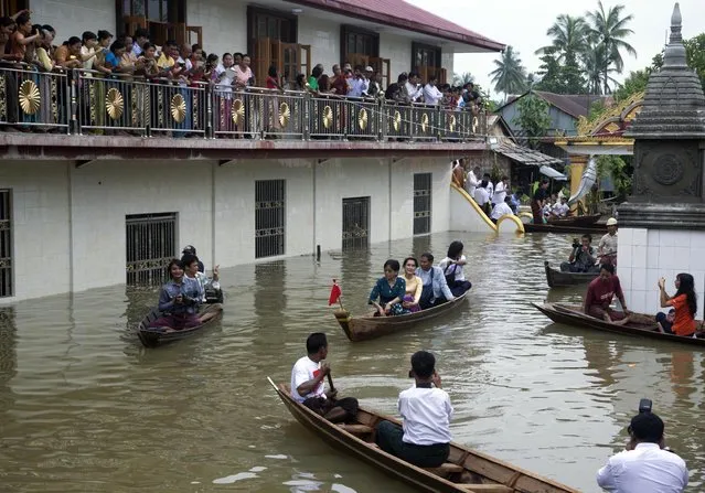 Myanmar opposition leader Aung San Suu Kyi, center, rides a boat as she leaves after visiting a monastery where flood victims are sheltered in Bago, 80 kilometers (50 miles) northeast of Yangon, Myanmar, Monday, August 3, 2015. A report issued Saturday by the U.N. Office for the Coordination of Humanitarian Affairs cited Myanmar disaster officials estimating that more than 156,000 people had been affected by flooding. (Photo by hin Maung Win/AP Photo/)