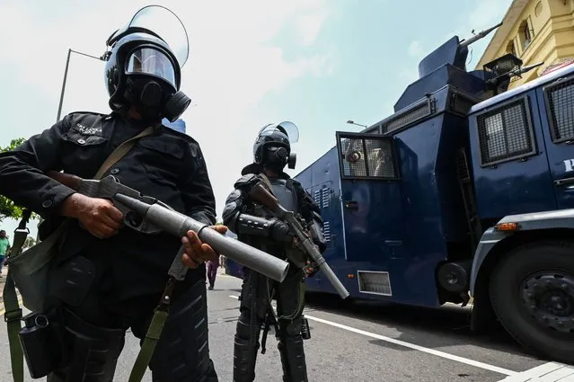 Police personnel stand guard outside the President's office as his supporters and anti-government protesters clash in Colombo on May 9, 2022. Violence raged across Sri Lanka late into the night on May 9, 2022, with five people dead and some 180 injured as prime minister Mahinda Rajapaksa quit after weeks of protests. (Photo by Ishara S. Kodikara/AFP Photo)