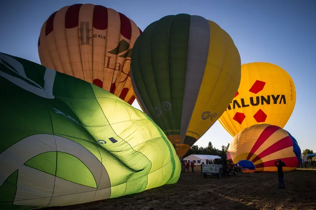 Hot air balloons are inflated at the European Balloon Festival on July 10, 2014 in Igualada, Spain. The early morning flight of over 30 balloons was shorter than expected due to windy weather. This flight is organised as a curtain raiser for the four-day European Balloon Festival. Now is the 18th year of the most important hot air Balloon event in Spain and one of the biggest in Europe. (Photo by David Ramos/Getty Images)
