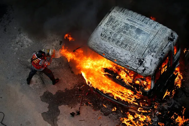 A fireman tries to extinguish a fire during a rally against Venezuela's President Nicolas Maduro in Caracas, Venezuela April 24, 2017. (Photo by Carlos Garcia Rawlins/Reuters)