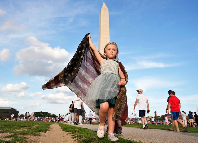 Sophia Liddiard, age four-and-a-half, from Long Beach, California, carries an American flag as crowds gather to watch the annual 4th of July fireworks display on the National Mall in Washington DC on Tuesday, July 4, 2023. (Photo by Ken Cedeno/UPI/Rex Features/Shutterstock)