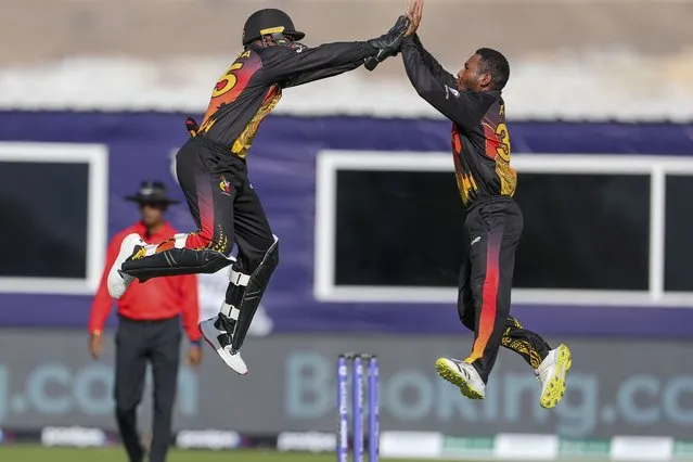 Papua New Guinea's Kiplin Doriga, left, celebrates with teammate Simon Atai after the dismissal of Scotland's Matthew Cross eduring the Cricket Twenty20 World Cup first round match between Scotland and Papua New Guinea in Muscat, Oman, Tuesday, October 19, 2021. (Photo by Kamran Jebreili/AP Photo)