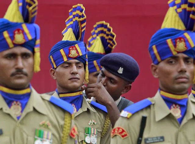 An Indian paramilitary soldier adjusts the uniform of his comrade during Independence Day celebrations. (Photo by Jayanta Dey/Reuters)