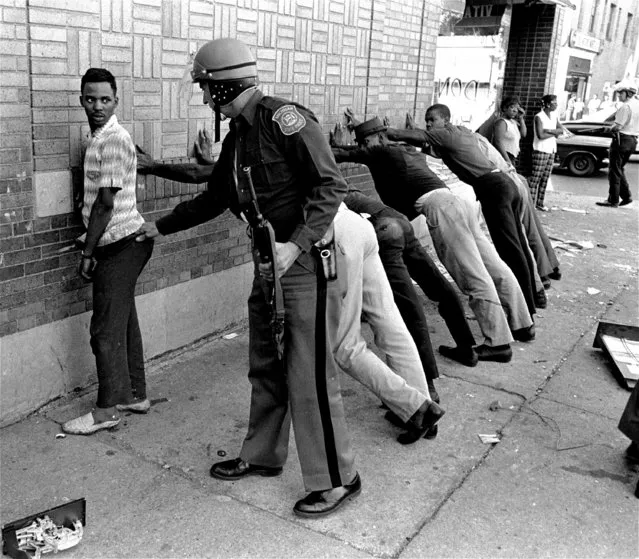 In this July 24, 1967 file photo, a Michigan State police officer searches a youth on Detroit's 12th Street where looting was still in progress after the previous day's rioting. The July 23, 1967 raid of an illegal after-hour’s club, though, was just the spark. Many in the community blamed frustrations blacks felt toward the mostly white police, and city policies that pushed families into aging and over-crowded neighborhoods. (Photo by AP Photo)