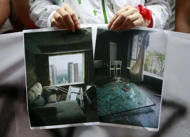 A resident evacuated from her home after last week's explosions at Binhai new district, shows pictures of the damage to her neighbors' houses at a rally demanding government compensation outside the venue of the government officials' news conference in Tianjin, China, August 17, 2015. (Photo by Kim Kyung-Hoon/Reuters)