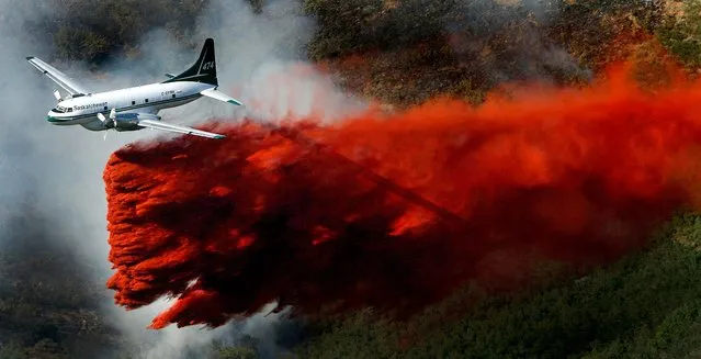 A plane drops its payload of fire retardant on a fire that burns just above homes in the mountains near Alpine, Utah