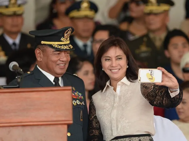 Philippines vice-president Leni Robredo (R) takes a selfie with a military officer during a military parade in honour of President Rodrigo Duterte (not pictured) at the military headquarters in Manila on July 1, 2016. Duterte was sworn in as the Philippines' president June 30 – and quickly launched a foul-mouthed vow to wipe out drug traffickers and even urged ordinary Filipinos to kill addicts. (Photo by Ted Aljibe/AFP Photo)