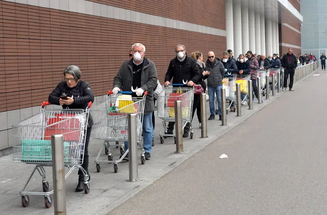 People wearing protective face masks lined up at a safe distance in front of a supermarket in Milan, Italy, 12 Mrch 2020. Tougher lockdown measures kicked-in in Italy on the day after Italian Premier Conte announced the day earlier that all non-essential shops should close as part of the effort to contain the coronavirus. Italy is on a nationwide lockdown until 03 April due to the novel cCovid-19 oronavirus crisis. (Photo by Andrea Canali/EPA/EFE)