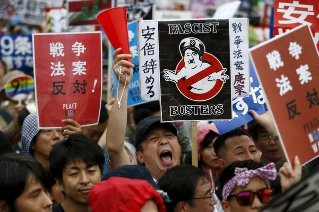 People hold placards and shout slogans as they protest against Japan's Prime Minister Shinzo Abe's security bill outside the parliament in Tokyo August 30, 2015. (Photo by Thomas Peter/Reuters)