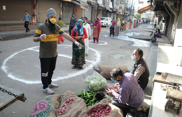 Indian people stand on designated areas to maintain social distancing as they queue to buy vegetables, during a government-imposed nationwide lockdown as a preventive measure against the COVID-19 coronavirus in Jalandhar, India 26 March 2020. India is facing the first day of the 21-day national lockdown decreed by Prime Minister Narendra Modi in an effort to slow down the spread of the pandemic COVID-19 disease caused by the SARS-CoV-2 coronavirus. There have been at least over 600 confirmed coronavirus infections throughout India and 10 deaths derived from the disease so far. (Photo by EPA/EFE/Stringer)