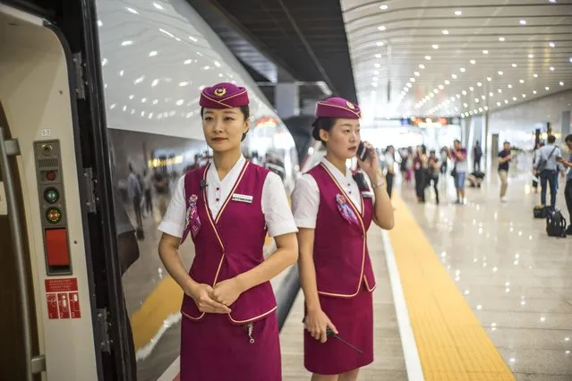 Chinese hostesses welcome passengers on the platform before a “Fuxing” high-speed bullet train on the Beijing-Shanghai Railway (Jinghu Railway) leaves the Beijing South Railway Station for the Shanghai Hongqiao Railway Station in Beijing, China on September 21, 2017. Fuxing, China's newest high-speed bullet trains were officially launched between Beijing and Shanghai on Thursday (21 September 2017), at a speed of 350 kilometers per hour. The Fuxing bullet trains were unveiled on June 25 and are capable of a top speed of 400 km/h. The Fuxing has a monitoring system that slows the train in case of emergency or abnormal conditions. Telemetry allows a control center to monitor the train in real time. The Fuxing, which means “rejuvenation”, is a substantial upgrade on the Hexie, which means “harmony”. The Fuxing is more spacious and energy-efficient, with a longer life expectancy and better reliability. (Photo by Imaginechina/Rex Features/Shutterstock)