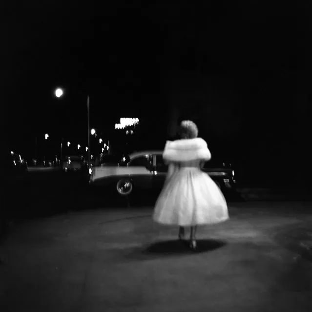 This 1957 photo provided by the Estate of Vivian Maier and John Maloof Collection a woman in a party dress walking towards a car in Miami. (Photo by Vivian Maier/Estate of Vivian Maier and John Maloof Collection via AP Photo)