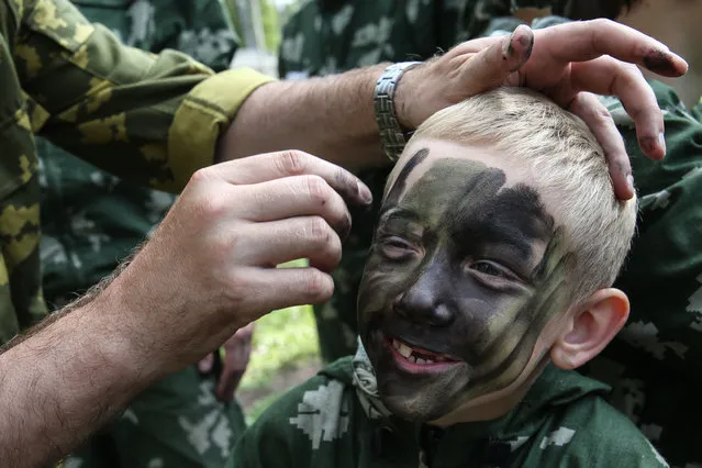 A group leader paints a boy’s face in preparation for a military sports game at a children’s camp in Moscow, Russia on July 29, 2016. (Photo by Vyacheslav Prokofyev/TASS)